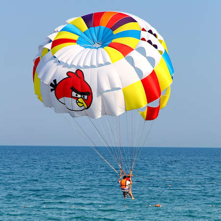 KEMER, TURKEY - AUGUST 12, 2015: Parasailing in a blue sky near sea beach. Parasailing is a popular recreational activity among tourists in Turkey.のeditorial素材