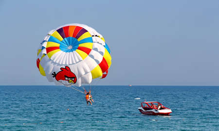 KEMER, TURKEY - AUGUST 12, 2015: Parasailing in a blue sky near sea beach. Parasailing is a popular recreational activity among tourists in Turkey.のeditorial素材