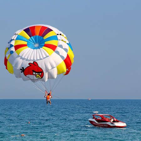 KEMER, TURKEY - AUGUST 12, 2015: Parasailing in a blue sky near sea beach. Parasailing is a popular recreational activity among tourists in Turkey.のeditorial素材