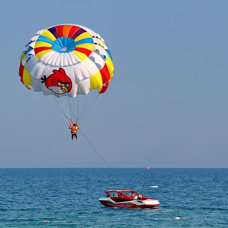 KEMER, TURKEY - AUGUST 12, 2015: Parasailing in a blue sky near sea beach. Parasailing is a popular recreational activity among tourists in Turkey.のeditorial素材