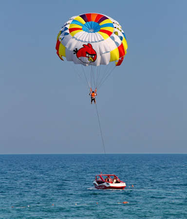 KEMER, TURKEY - AUGUST 12, 2015: Parasailing in a blue sky near sea beach. Parasailing is a popular recreational activity among tourists in Turkey.のeditorial素材