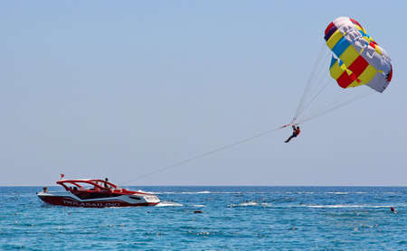 KEMER, TURKEY - AUGUST 13, 2015: Parasailing in a blue sky near sea beach. Parasailing is a popular recreational activity among tourists in Turkey. For editorial use only.のeditorial素材