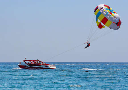 KEMER, TURKEY - AUGUST 13, 2015: Parasailing in a blue sky near sea beach. Parasailing is a popular...