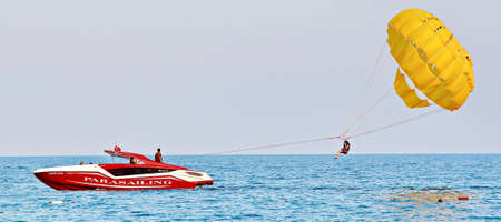 KEMER, TURKEY - AUGUST 14, 2015: Parasailing in a blue sky near sea beach. Parasailing is a popular recreational activity among tourists in Turkey. For editorial use only.のeditorial素材