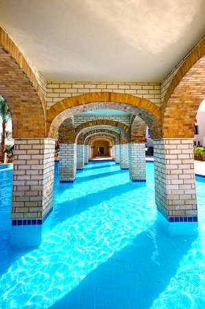 Panoramic swimming pool under bridge in resortの写真素材