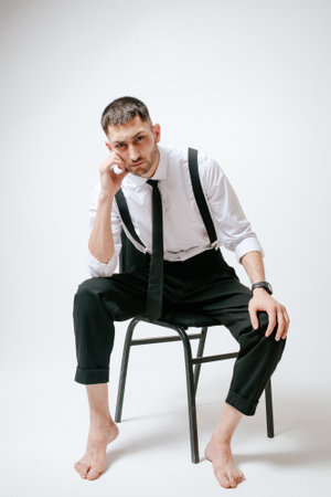A man with white shirt and tie sits on a chair in studio. Barefootの写真素材