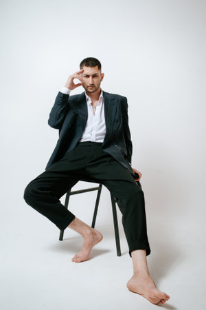 Handsome man, fashion model sits on chair, barefootの写真素材