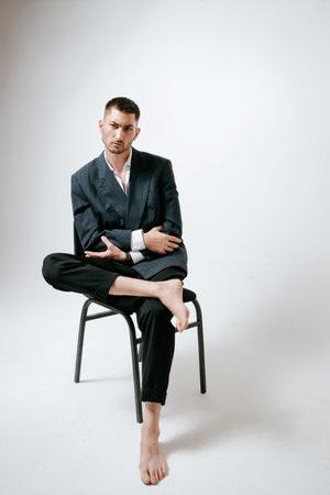 Handsome man, fashion model sits on chair, barefootの写真素材