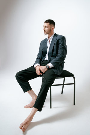 Handsome man, fashion model sits on chair, barefootの写真素材
