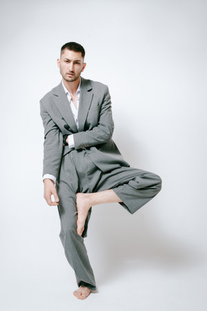Fashion man model in gray suit, barefoot, shoot in studio