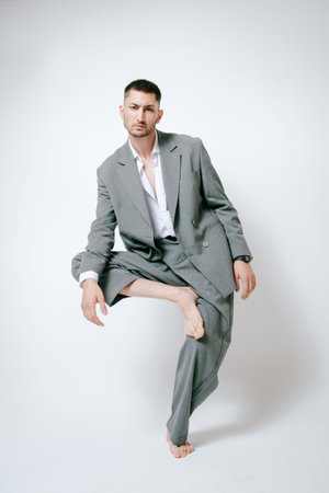 Fashion man model in gray suit, barefoot, shoot in studioの写真素材
