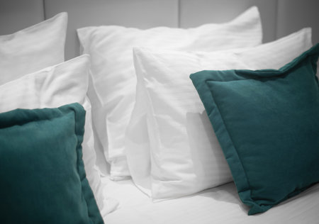 White and green pillows in room. Bedroom