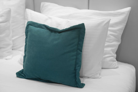 White and green pillows in room. Bedroom in hotel