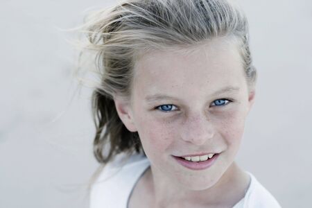 A close-up portrait of a pretty smiling, blonde haired teenage girl outdoors.の写真素材