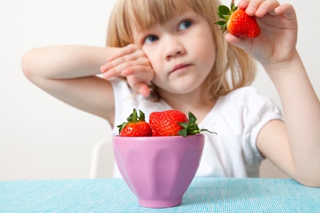 Little girl with a bowl of delicious strawberriesの写真素材