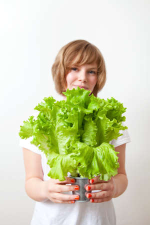 Young caucasian woman holding fresh green lettuceの写真素材