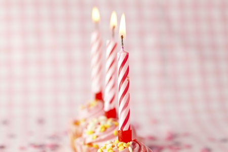 Close-up of pink muffins with party candles. Studio shot.