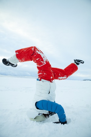 Woman doing yoga and a headstand in snow on a white winter dayの写真素材