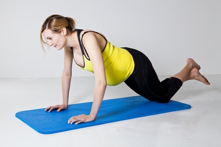 Pregnant woman doing a chest muscle strengthening push-up exercise on a matの写真素材