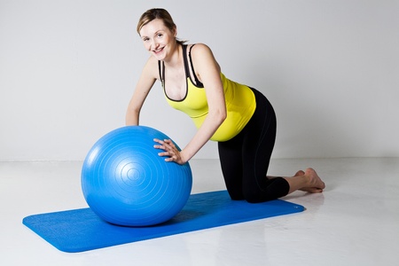 Pregnant woman doing a chest muscle strengthening push-up exercise on a fitness ballの写真素材