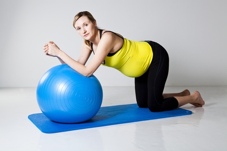 Pregnant woman doing an abdominal core strengthening exercise using a fitness ball on a matの写真素材