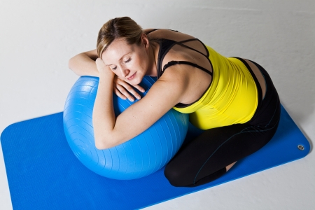 Pregnant woman relaxing while leaning against a fitness ball on a matの写真素材