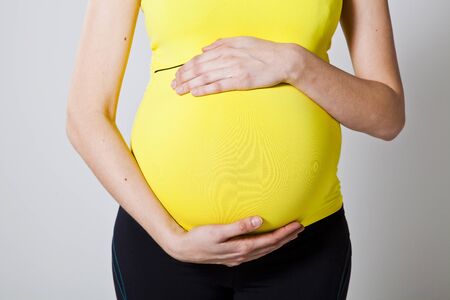 Close-up of pregnant belly with hands on the belly holdingの写真素材