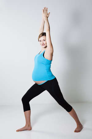 Pregnant woman doing a yoga stretching and balance exercise with arms above headの写真素材