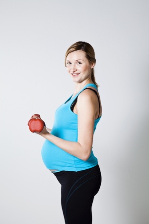 Pregnant woman exercising the bicep muscles with dumbbellsの写真素材