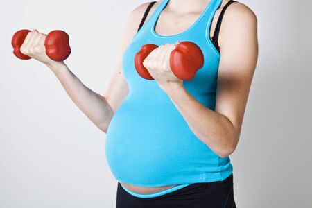 Pregnant woman exercising the bicep with dumbbellsの写真素材