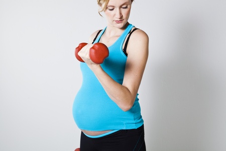 Pregnant woman exercising the bicep muscles with dumbbellsの写真素材