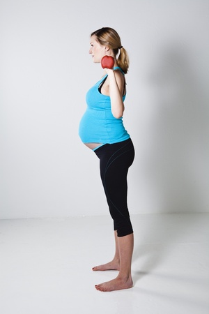 Pregnant woman exercising the shoulder muscles with dumbbellsの写真素材