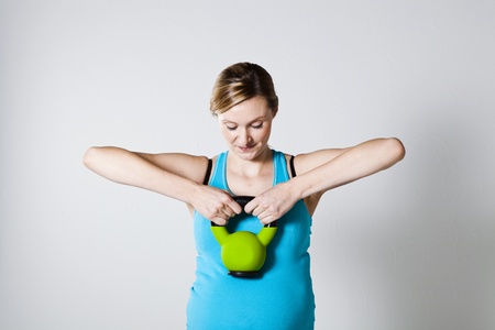 Pregnant woman doing shoulder muscle strengthening exercise with kettlebellの写真素材