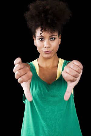 Young athletic woman with thumbs down. Studio shot with black backgroundの写真素材