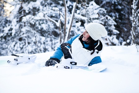 Female snowboarder resting in snow with snowboard in beautiful cold winter weatherの写真素材