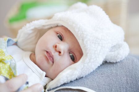 Portrait of a cute newborn baby girl lying wearing a fur hatの写真素材
