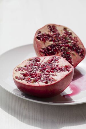 Close-up of fresh and delicious pomegranate halves on a plateの写真素材
