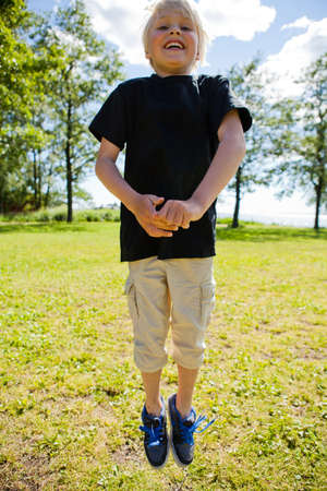 Portrait of a happy boy jumping outdoors on a beautiful summer day