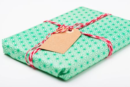 Close-up of simple gift package with green wrapping and plain cardboard tagの写真素材