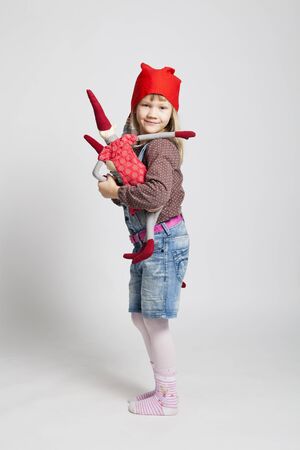Studio portrait of happy smiling young girl holding Christmas elf doll in standingの写真素材