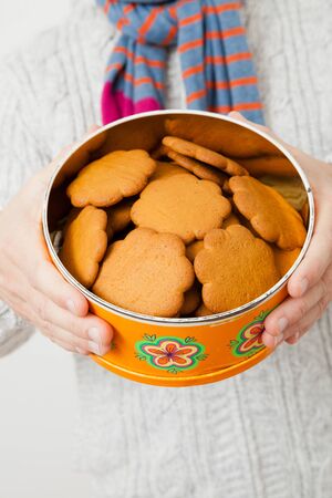 Tin of gingerbread biscuits being held up and presented by man wearing scalfの写真素材