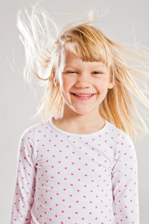 Studio portrait of happy smiling young girl with wind blowing her hairの写真素材