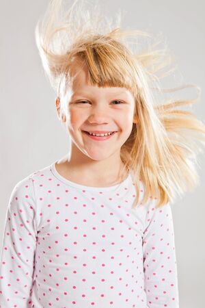 Studio portrait of happy smiling young girl with wind blowing her hairの写真素材
