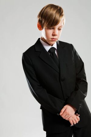 Studio portrait of serious looking young boy wearing black suitの写真素材