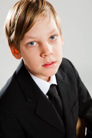 Closeup studio portrait of young boy wearing black suitの写真素材