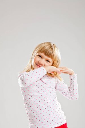 Studio portrait of happy smiling young girl looking forwards with raised handsの写真素材