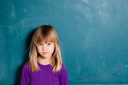 Portrait of a young girl standing in front of blank chalkboardの写真素材