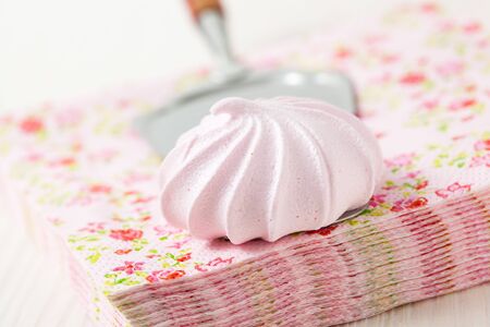 Pink meringue resting on server and serviettesの写真素材