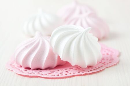 White and pink meringues resting on pink decorative mat on light backgroundの写真素材