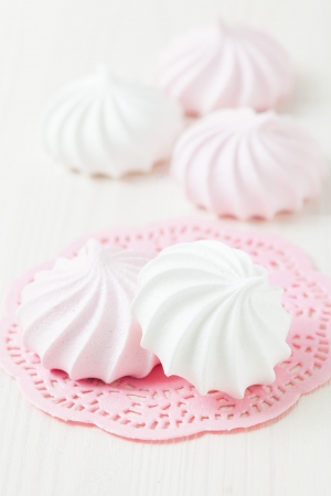White and pink meringues resting on pink decorative mat on light backgroundの写真素材